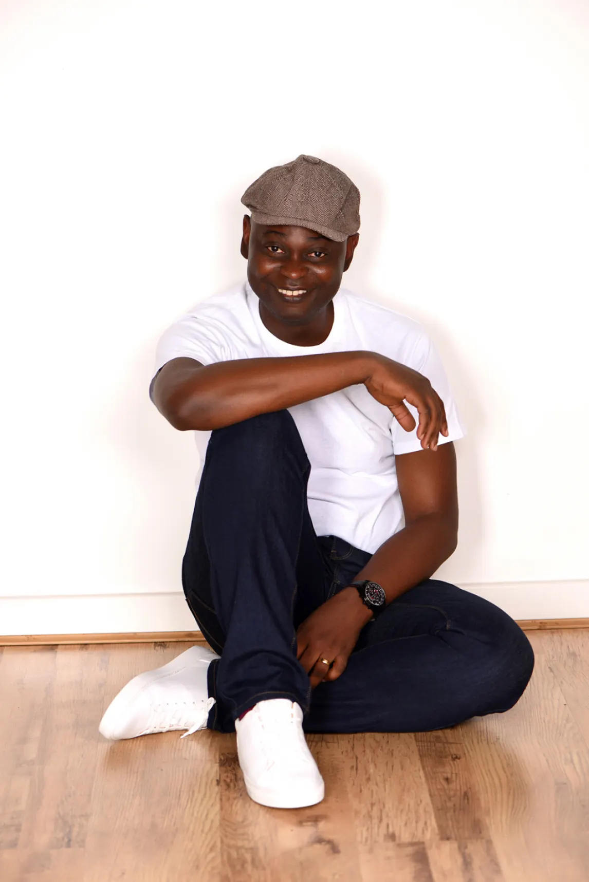 Yemi Alafifuni sitting on the floor against a bare wall, photographed in August 2020